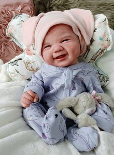 a smiling baby wearing a pink hat and holding a stuffed animal