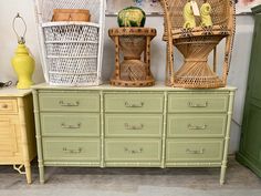 three wicker chairs sitting on top of a green dresser next to baskets and vases