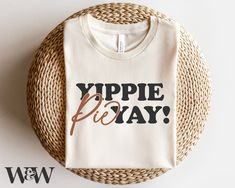 a white t - shirt with the words yppie play on it sitting next to a wicker basket