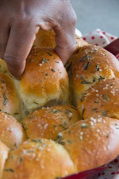 a person is picking up some bread from a red dish with white polka dots on it