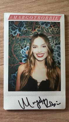 an autographed photo of a woman with long hair and red lipstick on a wooden table