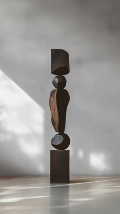 a tall wooden sculpture sitting on top of a hard wood floor next to a white wall