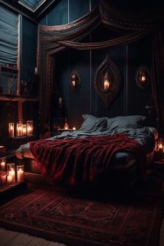 a bedroom with candles on the floor and a bed in the middle that has a red blanket over it