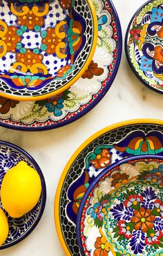 colorful plates and bowls with lemons on the counter top in front of them,