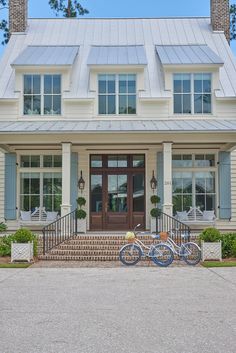 two bikes are parked in front of a large white house with blue shutters and windows