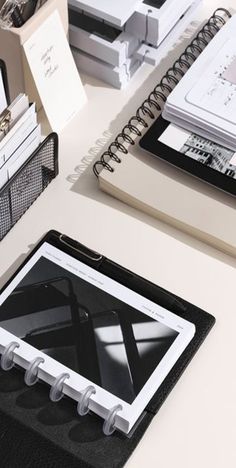 an open book sitting on top of a desk next to a binder and pen