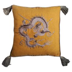 a yellow pillow with a dragon embroidered on it