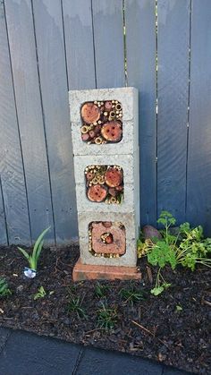 there is a stone sculpture with buttons on it in front of a fence and flowers