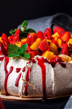 a cake covered in fruit and drizzled with red sauce on it's side