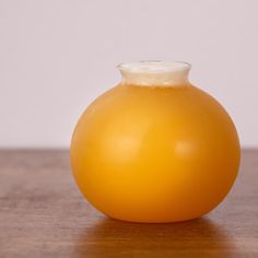 a yellow vase sitting on top of a wooden table