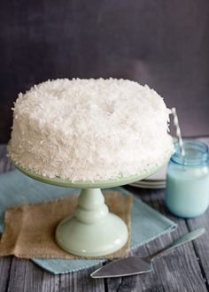 a cake with white frosting sitting on top of a table next to a jar