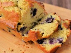 a loaf of blueberry bread sitting on top of a wooden cutting board