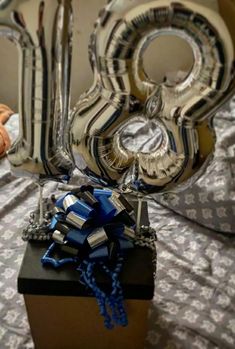 some balloons are in the shape of numbers on a bed with a blue ribbon tied to it