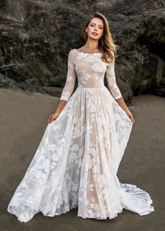 a woman in a wedding dress standing on the beach