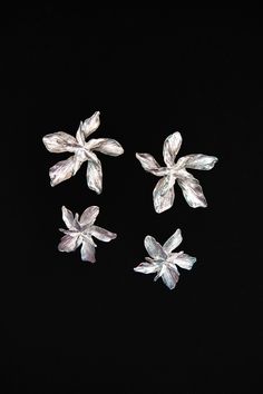 three pieces of glass sitting on top of a black surface with one flower in the middle