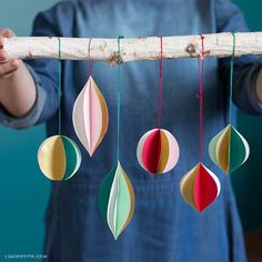 a person holding a branch with paper ornaments hanging from it