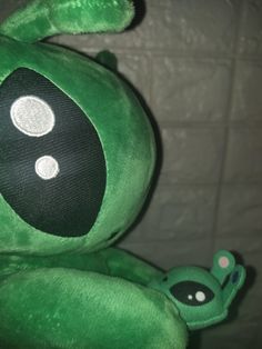 a green stuffed animal with white dots on it's eyes