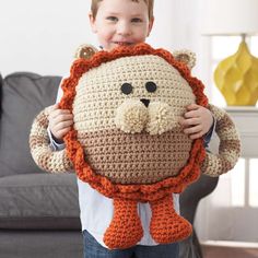 a little boy holding a crocheted lion pillow