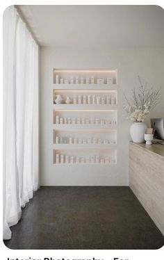 a white room with shelves and vases on the wall