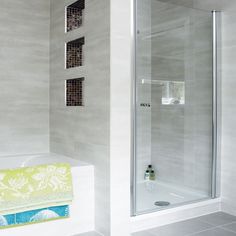 a bathroom with a walk in shower next to a white bathtub and tiled floor