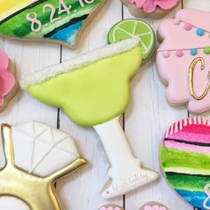 decorated cookies and cookie cutters are arranged on a white wooden table with pink flowers