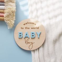 a wooden sign that says welcome to the world baby boy on it next to a blanket