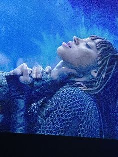 a woman with dreadlocks looking up at the sky on a television screen in front of her