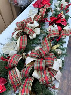 two christmas wreaths with bows and poinsettis on top of a table