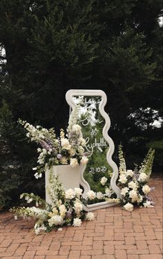 a wedding arch with flowers and greenery on the ground in front of some trees