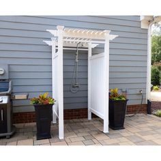 a white pergolan sitting on top of a patio next to two planters