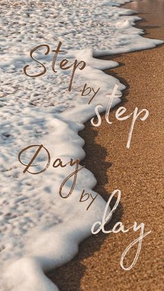 the words step by step day written in white ink on sand next to ocean waves