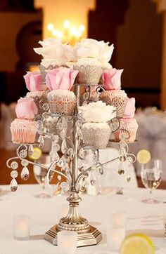 cupcakes and roses are on top of a silver candelabra at a wedding reception