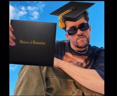 a man in sunglasses and a graduation cap is holding a book with the word diploma on it