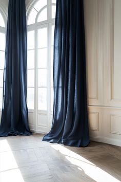 an empty room with two large windows and blue drapes hanging from the window sill