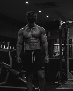 a shirtless man standing in front of a gym machine