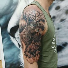 a man wearing a green tank top with an eagle and deer tattoo on his arm