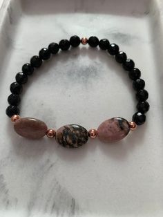 Another great bracelet for your stacks! Can be worn alone or added to any stack! Made with star cut black onyx stones, oval rhodonite center stones and rose gold hematite accent beads. Onyx is a protection stone. Helps to bring protection, strength and focus. Rhodonite is a compassion stone. Helps to bring acceptance and forgiveness. 7mm Star Cut Black Onyx Gemstones Oval Rhodonite Center Stones 4mm Rose Gold Hematite Accents Measures at approx 7 inches. Please note the standard size is 7 inches Black Onyx Bracelets With Gemstone Beads, Elegant Onyx Bracelets With Faceted Beads, Black Onyx Gemstone Beaded Bracelets, Black Onyx Round Crystal Bracelet, Elegant Hand-strung Onyx Beaded Bracelets, Bracelet Rose Gold, Black Onyx Stone, Onyx Bracelet, Protection Stones