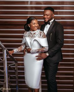 a man and woman standing next to each other in front of a stair case wearing formal attire