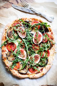 a pizza topped with lots of veggies on top of a table