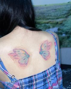 the back of a woman's shoulder with butterfly tattoos on her upper and chest