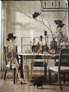 a skeleton sitting at a table in front of a wall with halloween decorations on it