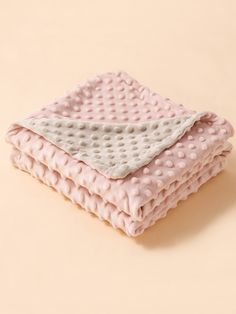 two blankets folded on top of each other in pink and white polka dotty fabric