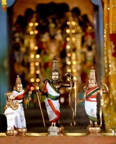 three small figurines are displayed in front of a decorated stage with lights behind them