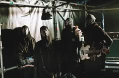 three people in masks are playing guitars and singing