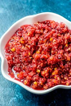 a white bowl filled with red sauce on top of a blue tablecloth next to a spoon