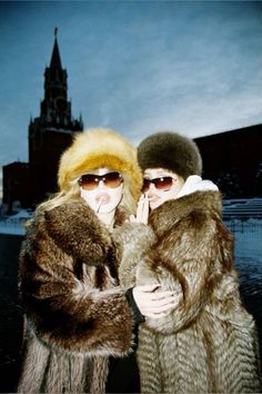 two women standing next to each other in front of a building