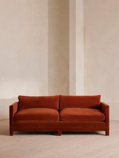 an orange couch sitting on top of a hard wood floor next to a white wall