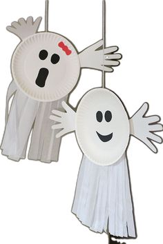 two paper plates with ghost faces hanging from the ceiling