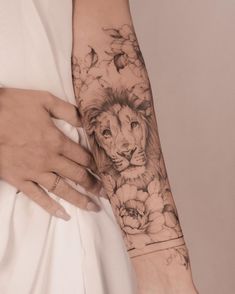 a woman's arm with a lion and flowers tattoo on the left side of her arm