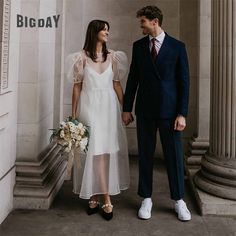 a man and woman standing next to each other in front of a building with columns